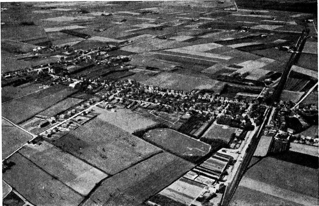 (Foto). Stationsby set fra luften. Til venstre den oprindelige landsby Nørre Alslev, til højre et stykke af banelinien til Nykøbing F., åbnet 1872. Langs den lige vej fra landsbyen til Nørre Alslev station skød stationsbyen op. I forgrunden moderne stadion.Fot. Sylvest Jensen.