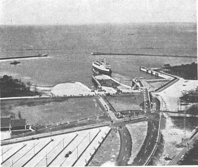 (Foto). Halsskov automobilfærgehavn, åbnet 1957. Til venstre parkeringsplads og restaurant; veje til til- og frakørsel, rampe til færgens øverste automobildæk. I havnen todæksfærgen »Halsskov«.Aero luftfot. 1957.