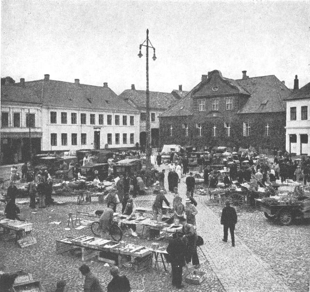 (Foto). Torvedag i Viborg. På købstædernes torve, hvor i middelalderen og også senere en væsentlig del af byens omsætning var koncentreret (især ved markederne), falbyder endnu på bestemte ugedage omegnens bønder, gartnere o.a. deres produkter, et levn af en ældgammel omsætningsform.Fot. Jonals.