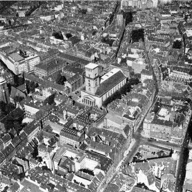 (Foto). Udsigt over en del af den gamle by omkring Vor Frue kirke (i billedets midte). Længst til højre Strøget (lodret i billedet) og Gammeltorv. Man bemærker de krumme gadelinjer og bebyggelsens opdeling på mindre grunde.