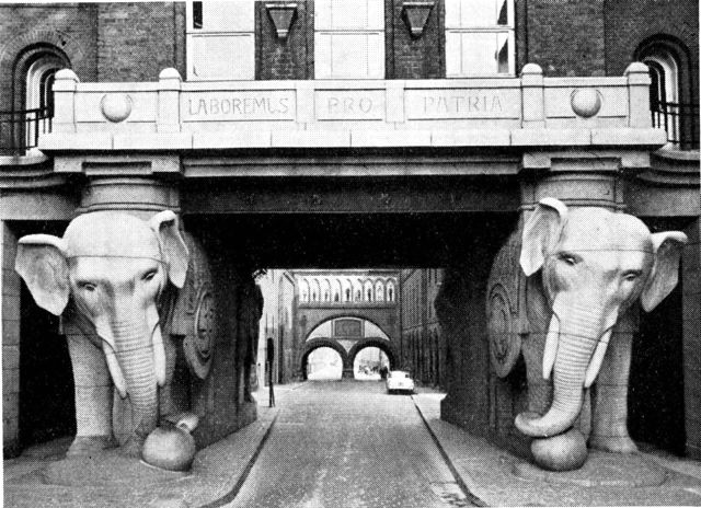 (Foto). Indkørsel til Carlsberg Bryggerierne fra vest gennem Elefantporten (fra 1901) med Carl Jacobsens valgsprog LABOREMUS PRO PATRIA. I baggrunden ses Dipylonporten.