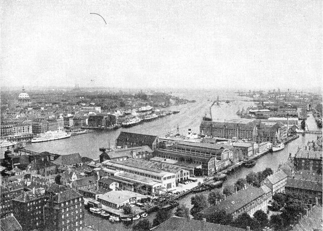 (Foto). Københavns havn set mod nord fra Vor Frelsers kirketårn. I forgrunden Christianshavns kanal med småbåde. På den anden side af Inderhavnen ses til venstre den lyse Malmøbåd ved Havnegade og nærmere billedets midte et par Jyllandsbåde ved Kvæsthusbroen. Længere ude Yderhavnen og Flådens Leje.