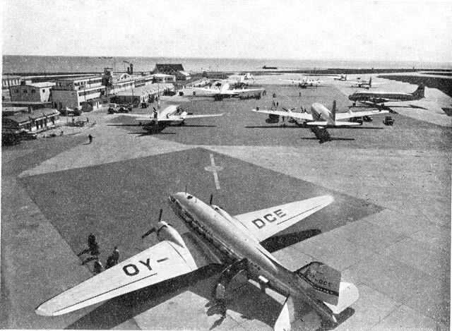 (Foto). Parti af Københavns Lufthavn med Øresund i baggrunden. Til venstre bl.a. den 1936–39 opførte administrationsbygning med senere udvidelser. Nærmest sundet »Krudthuset« (med højt mørkt tag).