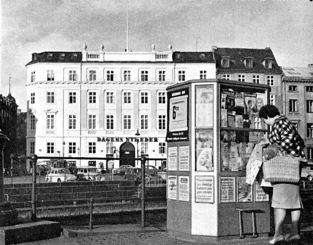 (Foto). Aviskiosk ved Højbro, en af de mange kiosker. der – spredt over hele byen – udgør et karakteristisk indslag i det københavnske gadebillede, og hvorfra en stor del af avisernes og ugebladenes oplag spredes til læserne. I baggrunden »Dagens Nyheder«’s bygning (opført 1796 som hotel Royal; bladhus fra 1877).