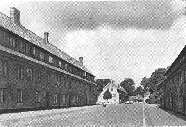 (Foto). Hovedgaden i Kastellet flankeret af de gamle stokke. I baggrunden skimtes Norgesporten.