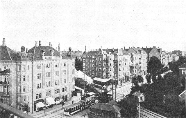 (Foto). Udsigt imod Bülowsvej med jernbaneoverskæringen for Nordbanen, fotografi o. 1910. Til venstre hjørnehuset ved Åboulevarden, til højre Landbohøjskolens bygninger. Nordbanen, som var anlagt 1863 gennem Frederiksbergs ubebyggede landdistrikt, skabte uforudsete trafikproblemer, da det moderne Frederiksberg så hurtigt voksede op.