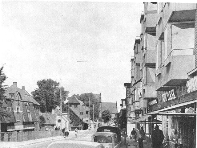 (Foto). Gadebillede fra Ballerup. I baggrunden den gamle landsbykirke, til venstre ældre stationsbyhuse, til højre moderne høj forstadsbebyggelse.