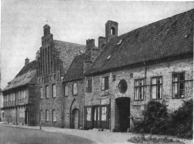 (Foto). Husrække ved nordsiden af Skt. Peders Kirkeplads; fra venstre bindingsværksgården nr. 3 fra 1606, derefter det gamle rådhus’s gavl og portfløj og til højre nr. 7 »Gøyernes gård«.