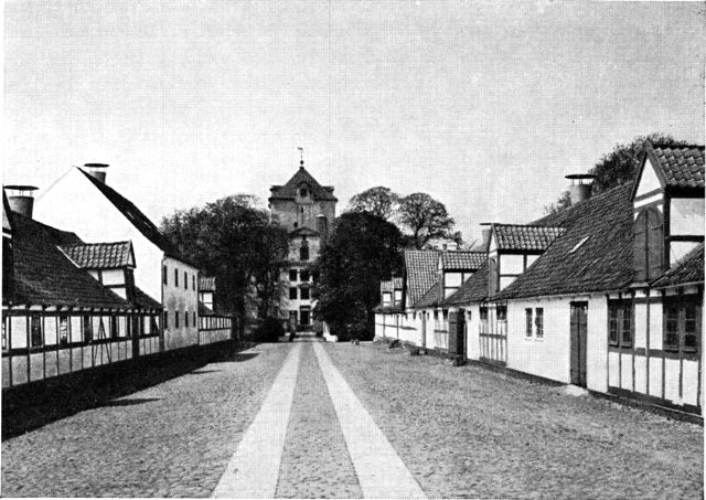 (Foto). »Bredgade« på Gjorslev med bindingsværksbygninger delvis fra Frederik IV.s tid, set fra øst mod hovedbygningen.
