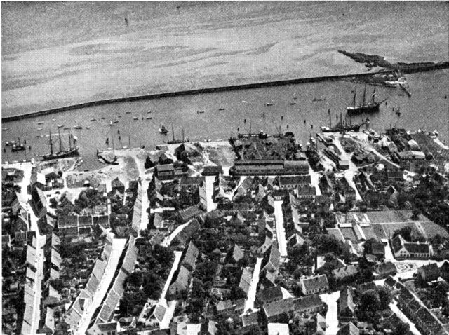 (Foto). Luftfotografi af den sydlige del af Marstal med havnen. Længst til venstre Prinsensgade, der fører fra torvet til havnen. Ved havnen skibsværfter til højre.