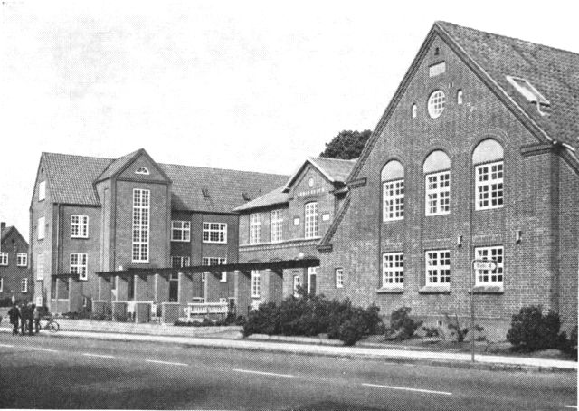 (Foto). Parti af Gjedved seminarium, bygninger ved hovedvej A10 (hovedbygning fra 1903 med nyere fløje fra 1910– til højre – og 1937 – til venstre).