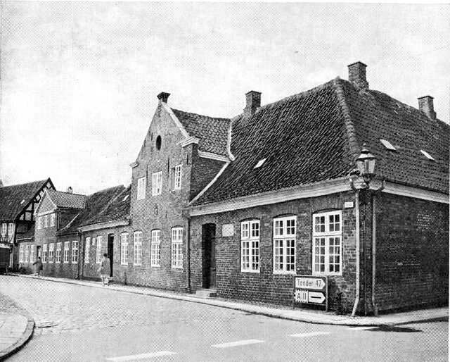 (Foto). Sparekassens friboliger (den gamle latinskole fra 1726) i Skolegade og (længere nede i gaden) Pastorinde Bangs stiftelse.