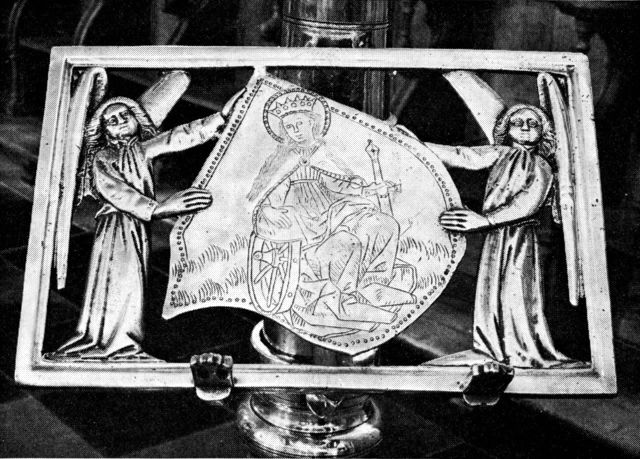 (Foto). Bogstol af messing på kandelaber i Ribe domkirke. På midtskjoldet graveret billede af Skt. Katharina.