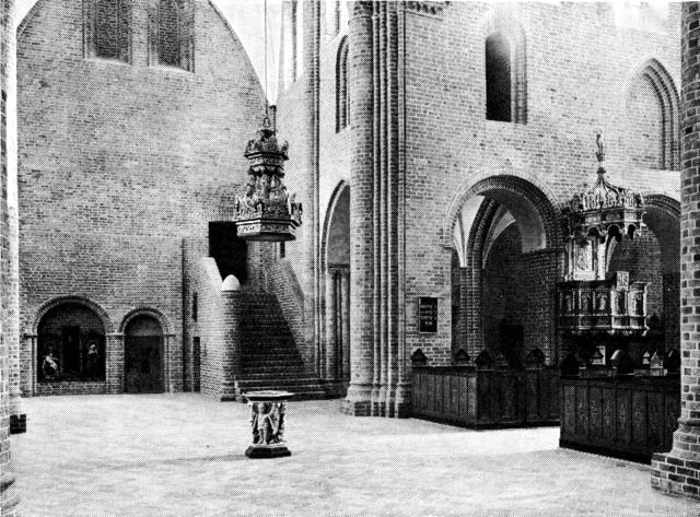 (Foto). Løgumkloster kirkes indre set fra nordre korsarm. Til højre en del af hovedskibet med prædikestolen, i midten trappen til dormitoriets dør i søndre korsarms gavl.
