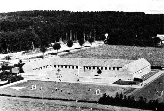 (Foto). Nørre Løgum centralskole ved Tornskov, set fra luften med den skovklædte bakkeø i baggrunden.
