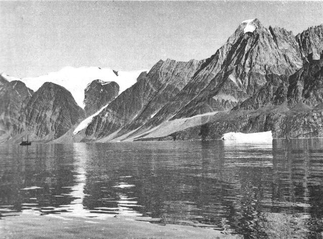 (Foto). Gnejs og gråvakke i Umanak området, østsiden af Inukavsait (1700 m). Gnejs underlejrer normalt i dette område de mørke gråvakker og ses ved kystlinien dels bag isfjeldet, dels bag motorkutteren. Den lyse bjergart øverst til højre er en stor gnejsfold, der er skudt ind over gråvakkerne ved en foldningsproces. (F.: T. C. R. Pulvertaft, GGU).