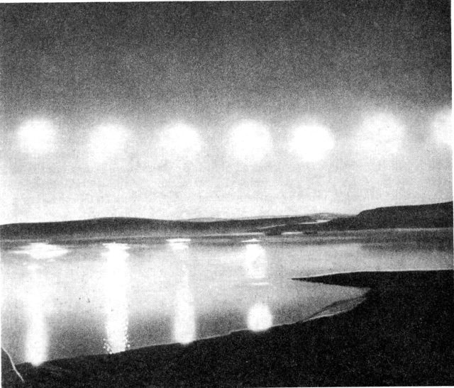 (Foto). Midnatsolen over Wolstenholme Fjord, Thule. De syv sole på den nedadgående bue i nord er eksponerede med 1/2 times mellemrum, juli 1936 fra kl. 22,30-01,30. (F.: Mogens Holm).