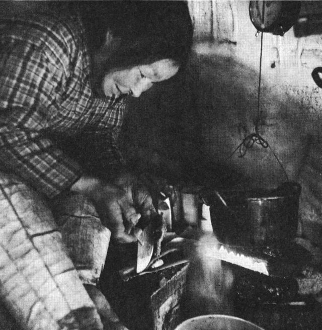(Foto). Samme snehytte som på foregående side. Spæklampen er tændt, og kød skæres ud til kogning. (F.: Chr. Vibe, Neqe 1941).