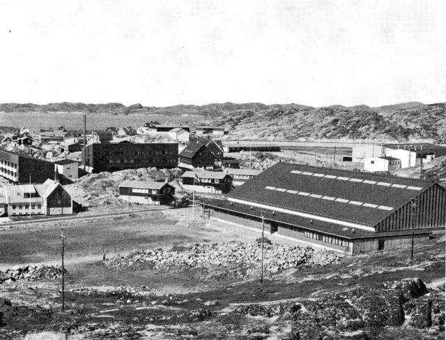 (Foto). Godthåb. Idrætshallen th. I midten th. sportsplads og heliport. På fjeldknolden i billedets centrum klosteret. (F.: Chr. Vibe 1969).