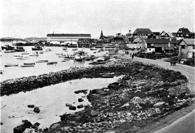 (Foto). Egedesminde havn med pakhuse, gamle og nye kirke. (F.: Chr. Vibe 1969).